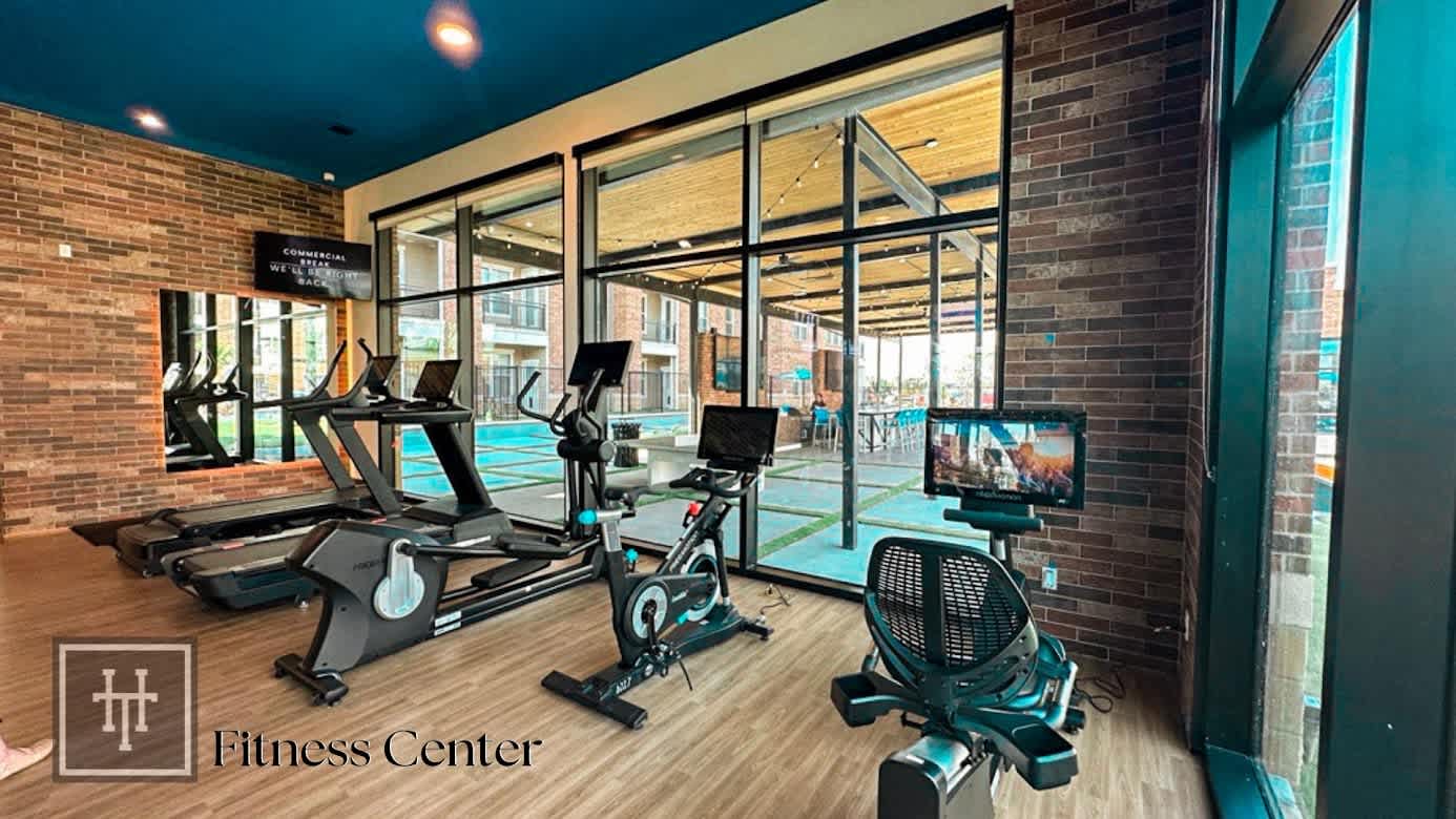A gym with cardio equipment and a pool in the background