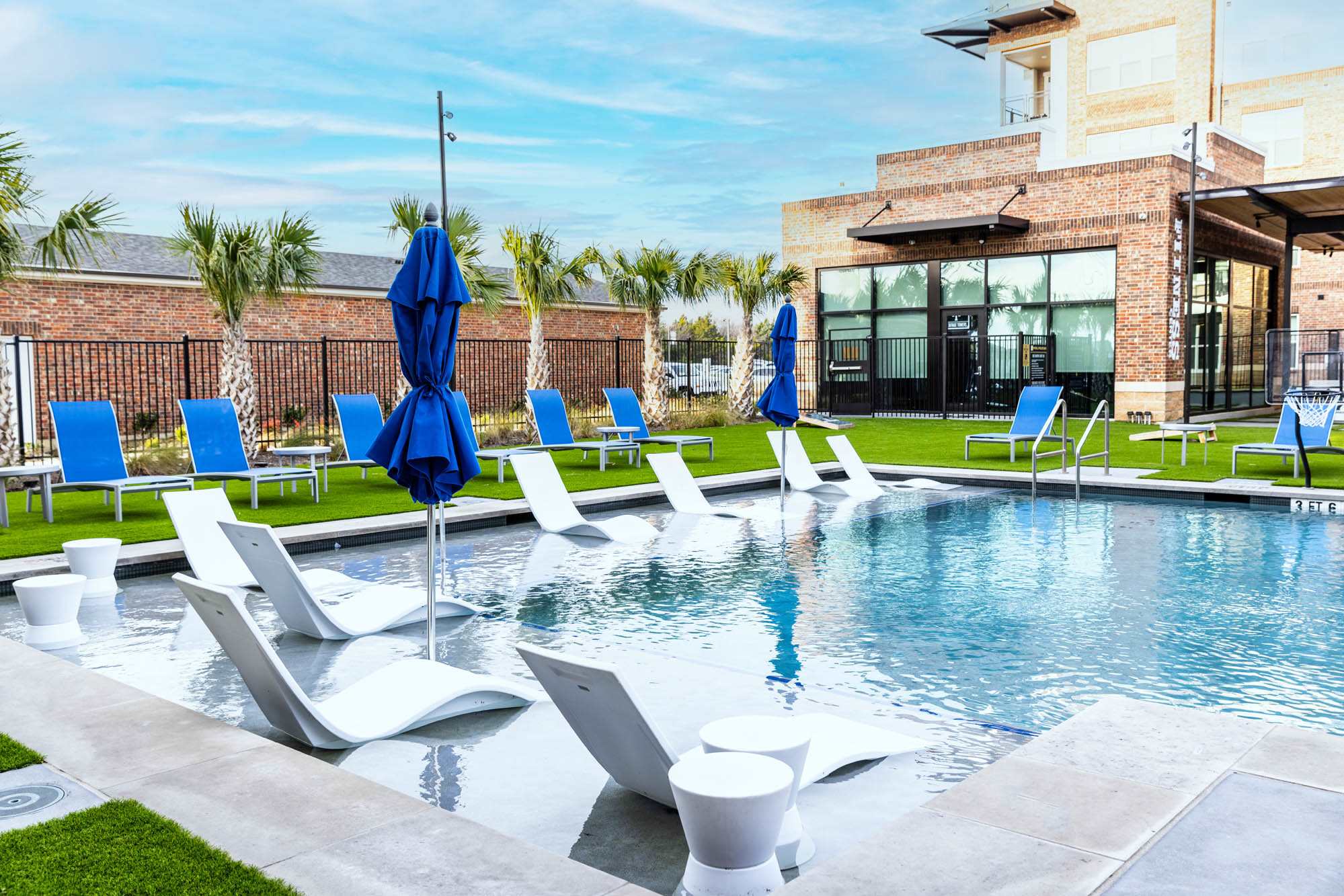 A swimming pool with chairs and umbrellas in front of a building