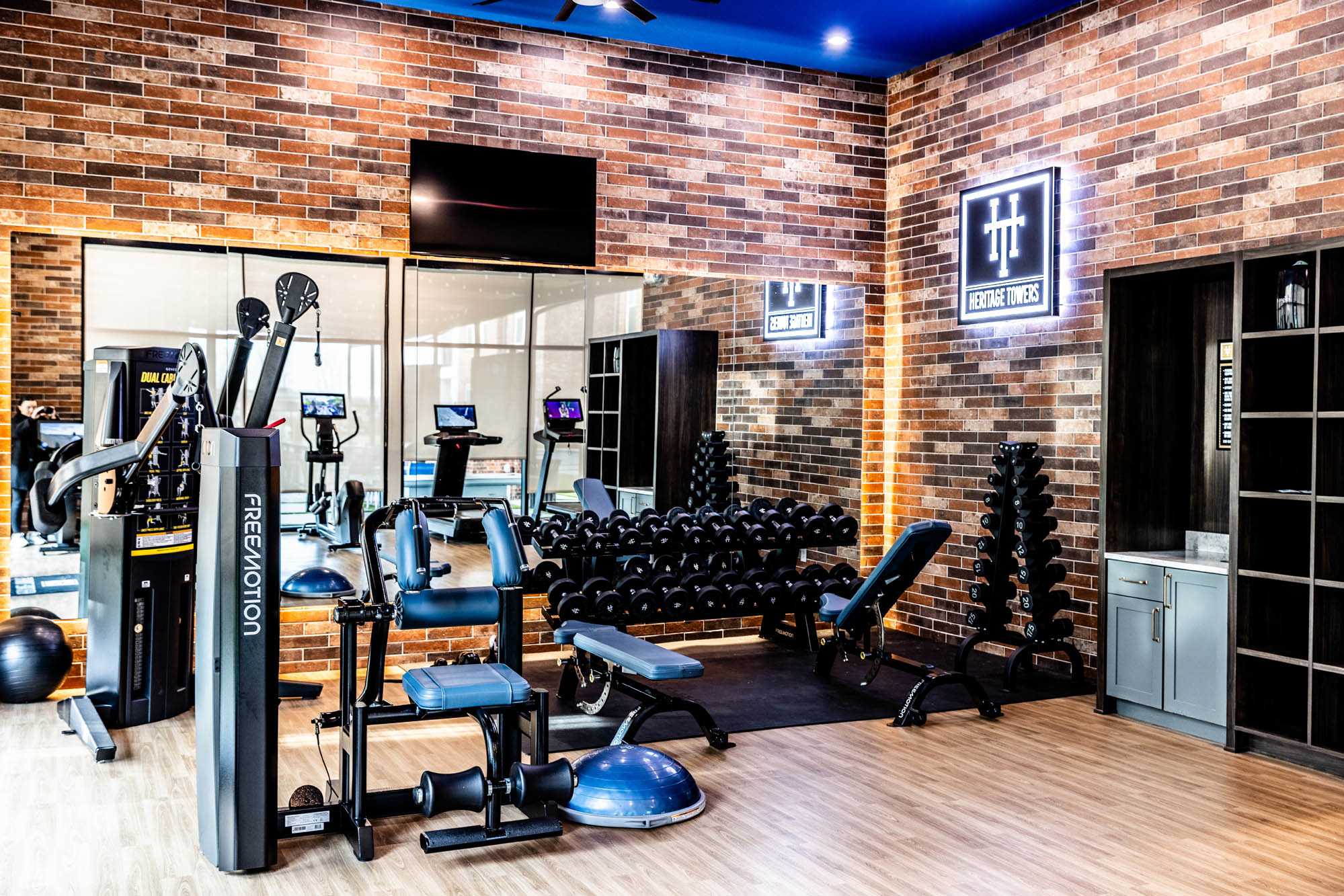 A gym with a lot of equipment and a brick wall