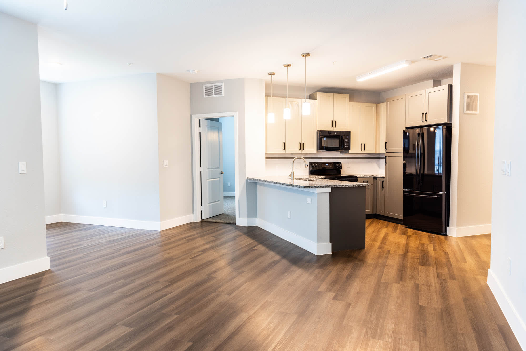 An empty living room and kitchen with wood flooring