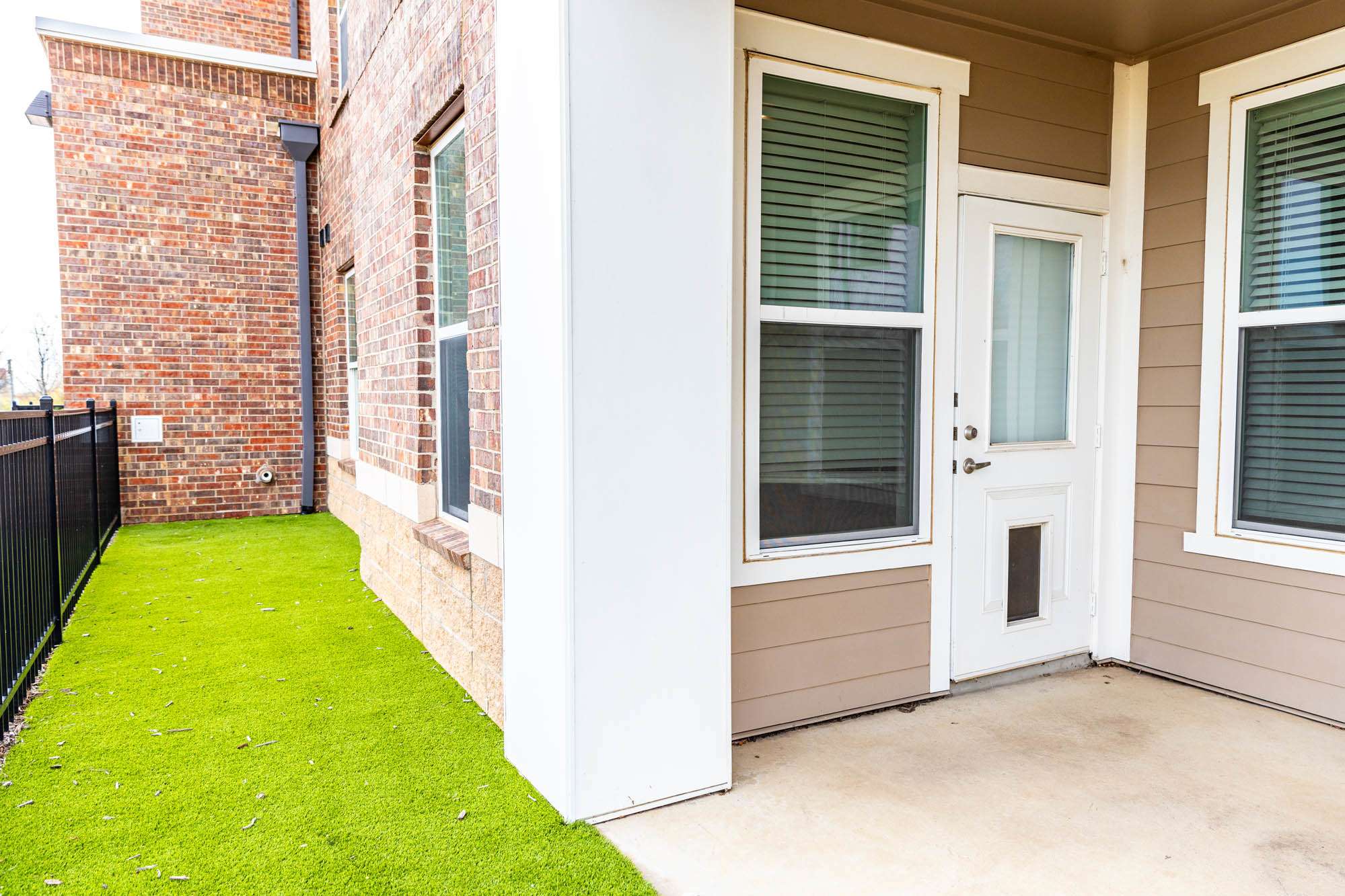The front porch of a brick building with grass